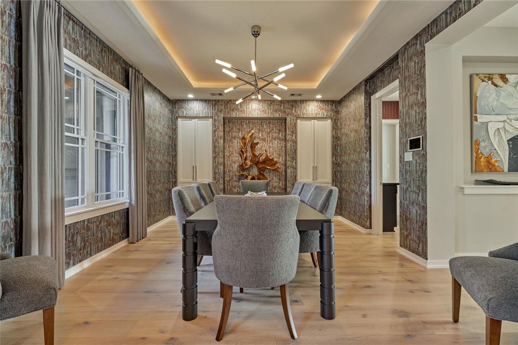 What better way to dazzle you and your guests than with this divine dining room boasting of opulent lighting, custom glam wallpaper and crisp white built-in cabinetry. 