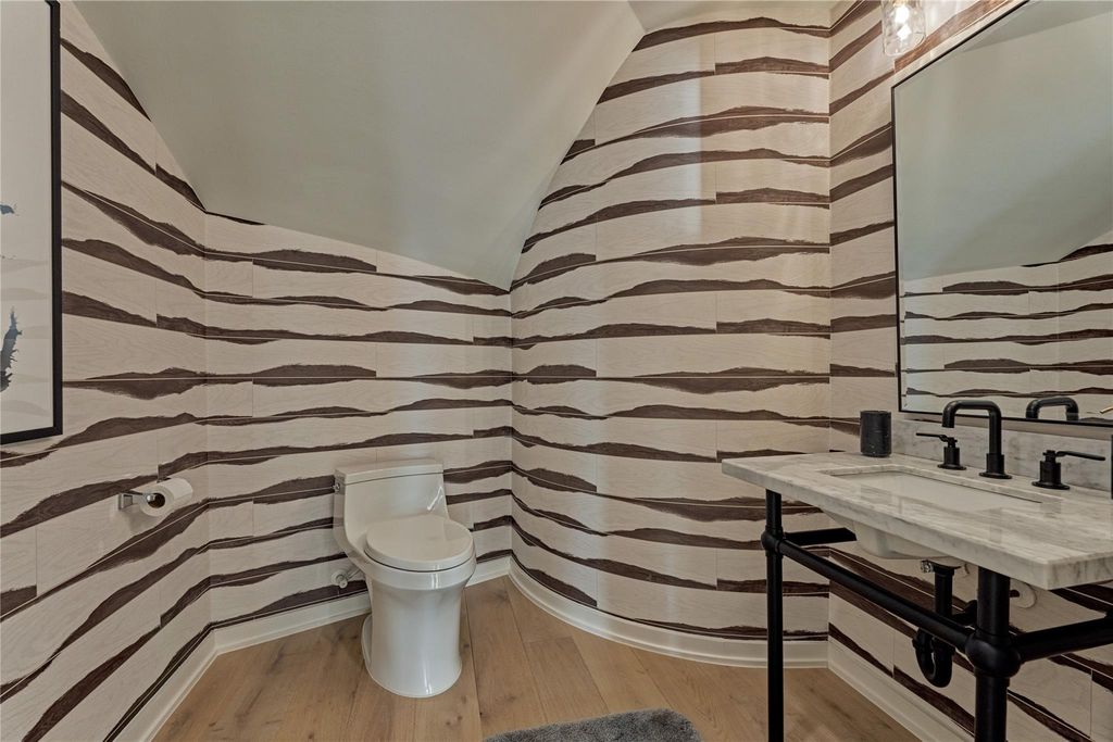 The half-bath features stylish wallpaper creating a dramatic flare. 